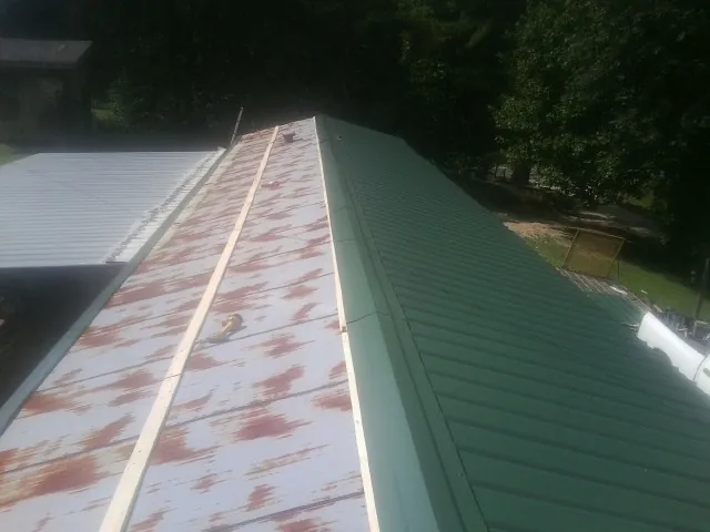 Old rusted panels beside newly installed green metal roofing — Wind Damage Roof Repair by Roofing Brothers in East Setauket