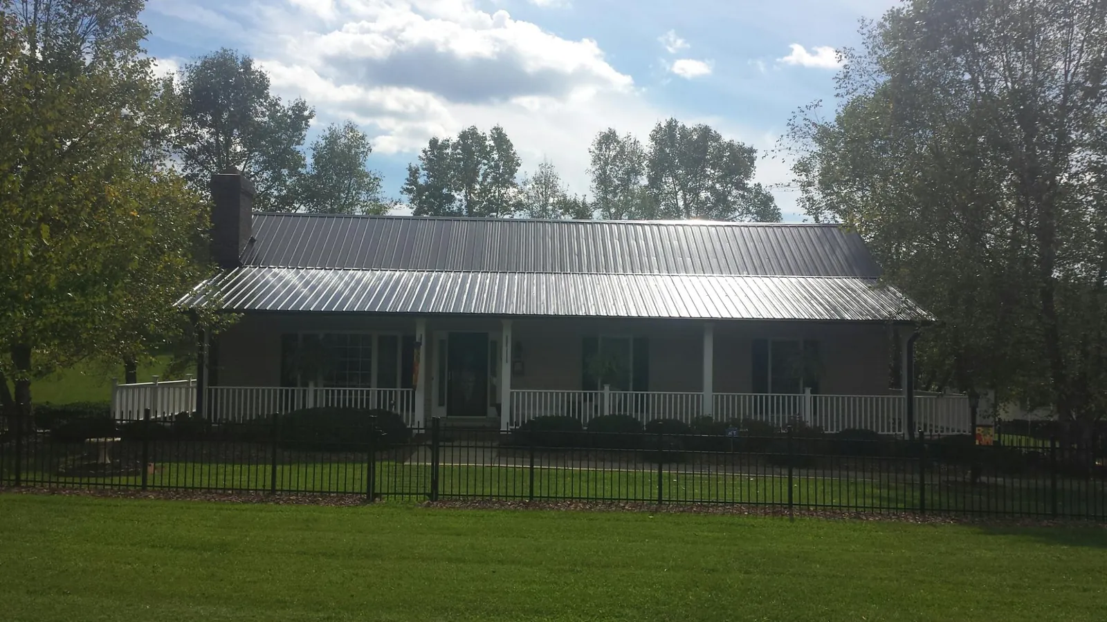 Gray metal roof on a brick ranch with a full width front porch — Gutter Guard Installation work by our crew in East Setauket