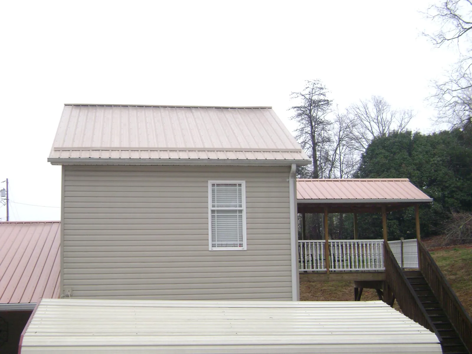 Tan metal roofs on a two story addition and attached porch, from a Roof Replacement job in East Setauket