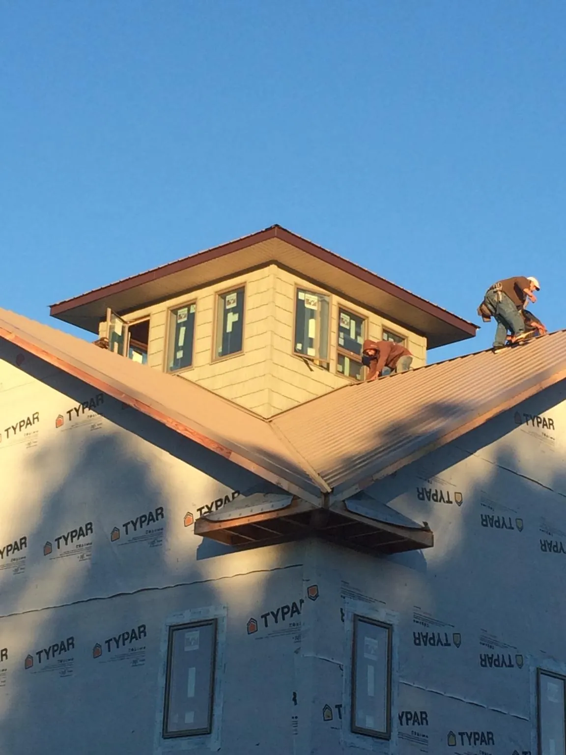 Roofers working around a rooftop cupola on a new metal roof at sunset — Roof Waterproofing in East Setauket by Roofing Brothers
